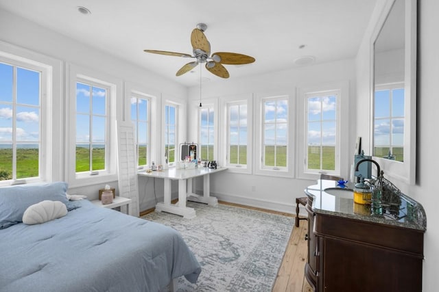 bedroom featuring light wood finished floors, baseboards, and a ceiling fan