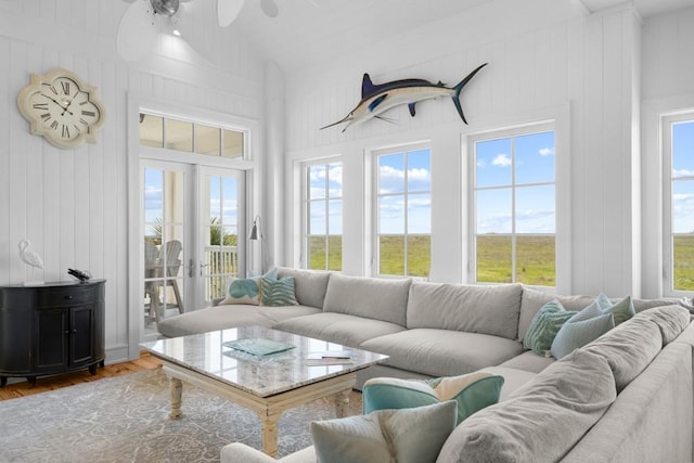 living area featuring vaulted ceiling, french doors, wood finished floors, and a wealth of natural light