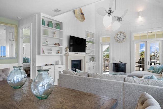 living area with french doors, built in features, visible vents, and a healthy amount of sunlight