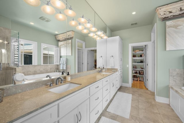 full bathroom featuring a garden tub, visible vents, a sink, and tile patterned floors