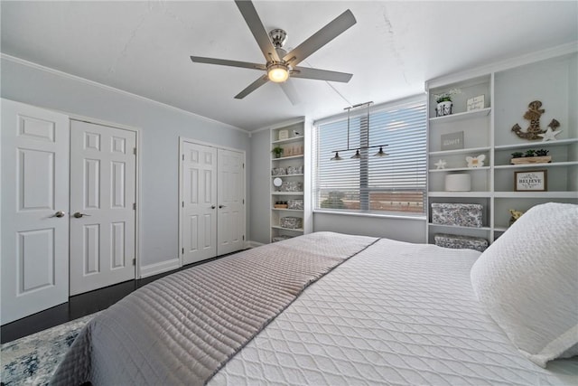 bedroom with baseboards, ornamental molding, ceiling fan, and two closets
