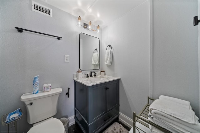bathroom with visible vents, baseboards, toilet, and vanity