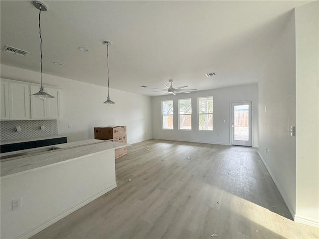 kitchen featuring white cabinetry, hanging light fixtures, light hardwood / wood-style flooring, ceiling fan, and backsplash