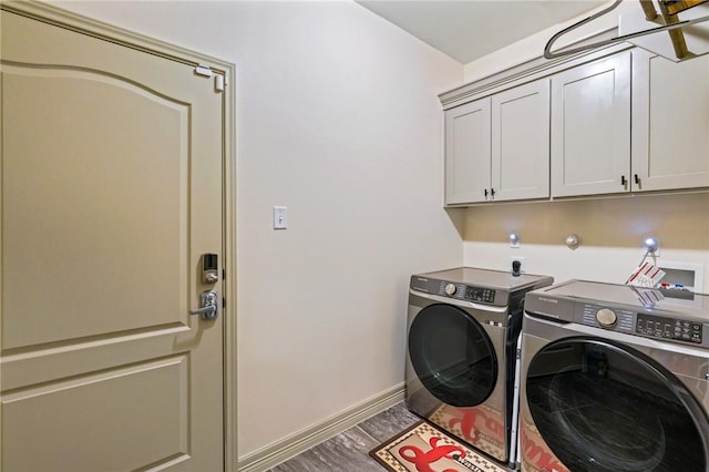 clothes washing area with hardwood / wood-style flooring, cabinets, and washing machine and clothes dryer