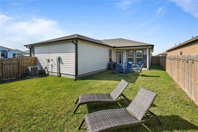 rear view of property featuring central AC unit and a lawn