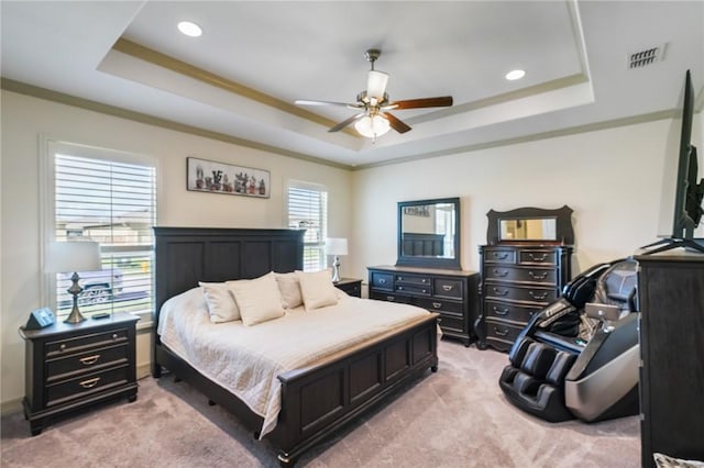 bedroom featuring ceiling fan, ornamental molding, light carpet, and a tray ceiling