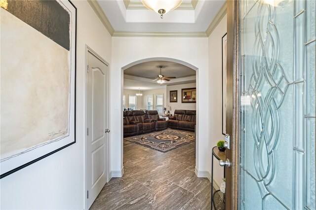 foyer with a raised ceiling, ceiling fan, and ornamental molding