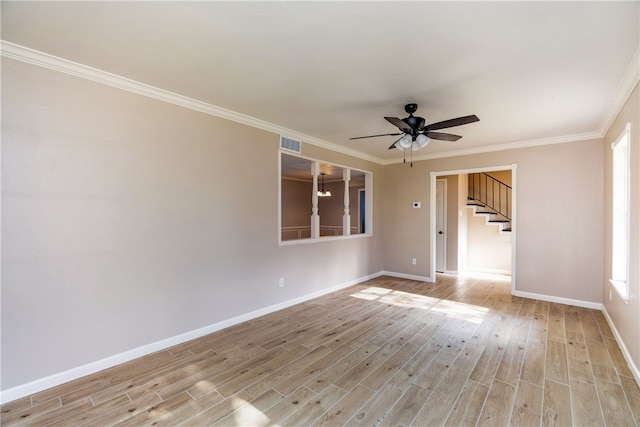 empty room featuring ceiling fan with notable chandelier, light hardwood / wood-style floors, and crown molding