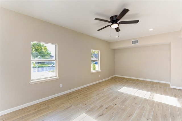 spare room featuring light wood-type flooring, a wealth of natural light, and ceiling fan