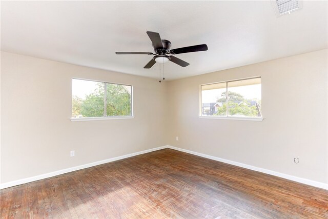 unfurnished room featuring plenty of natural light, dark wood-type flooring, and ceiling fan