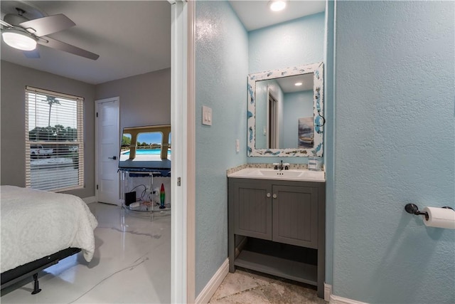 bathroom with ceiling fan, a textured wall, vanity, and baseboards