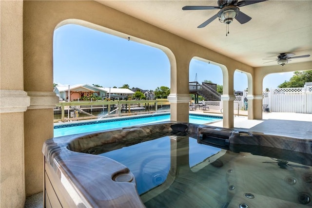 view of swimming pool with ceiling fan, fence, stairs, a fenced in pool, and a hot tub