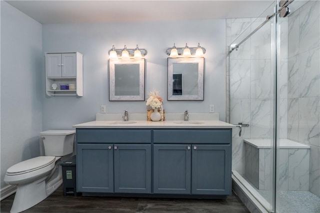 bathroom with toilet, a marble finish shower, and a sink