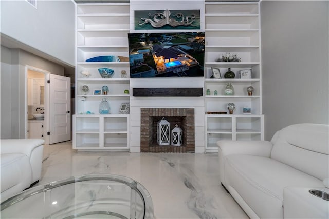 living room with marble finish floor, built in shelves, and a fireplace