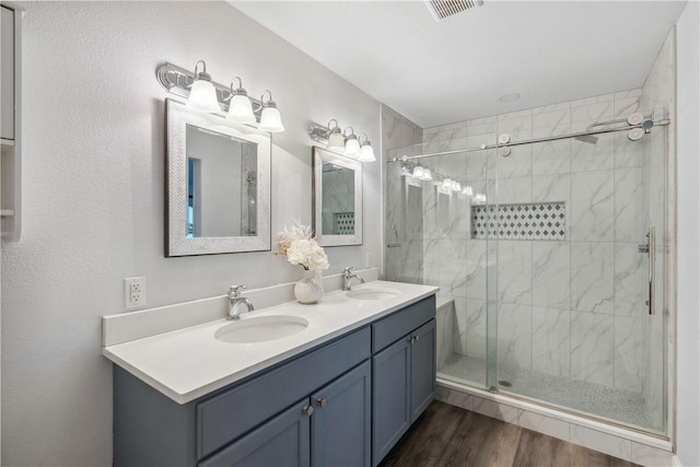 bathroom featuring a sink, visible vents, a shower stall, and wood finished floors