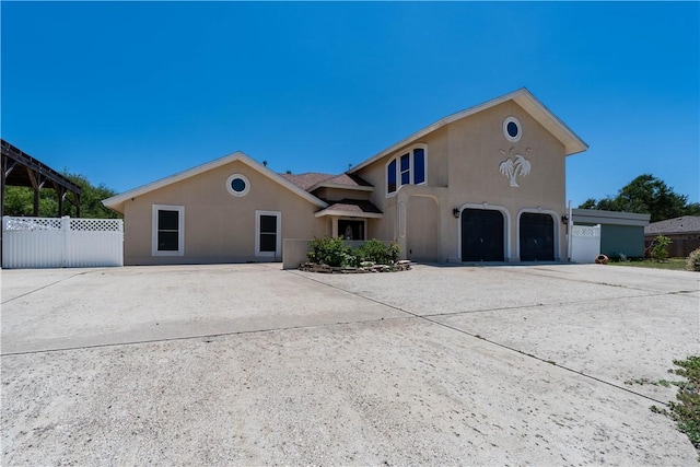 view of front of home featuring driveway, fence, and stucco siding