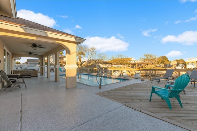 view of swimming pool with a deck, a fenced in pool, and a ceiling fan