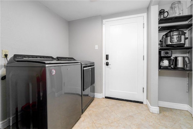 washroom with laundry area, washing machine and dryer, light tile patterned floors, and baseboards