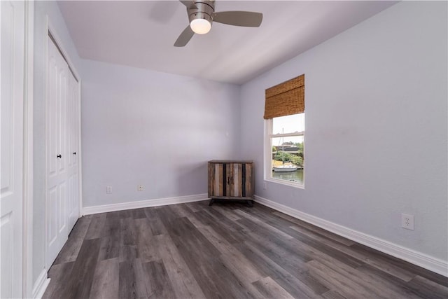 unfurnished bedroom with ceiling fan, dark wood-type flooring, a closet, and baseboards