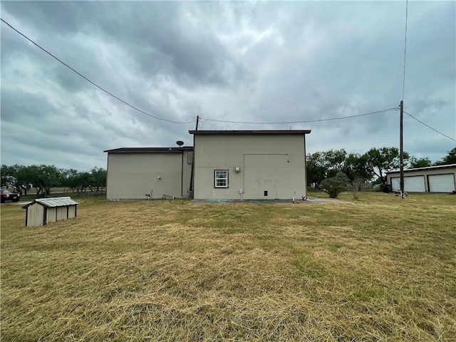 rear view of property featuring a lawn and an outbuilding