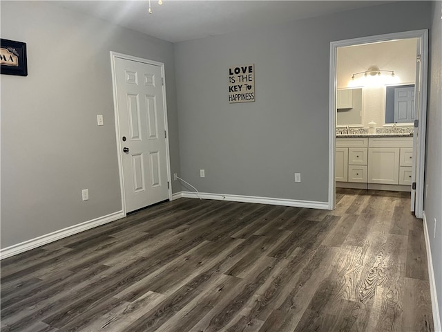 unfurnished bedroom featuring dark hardwood / wood-style floors and connected bathroom