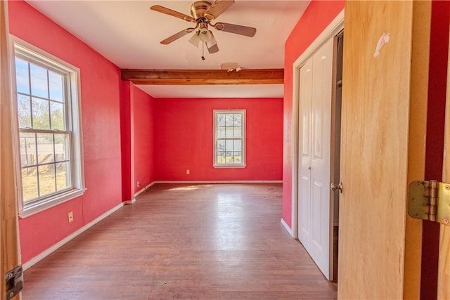 spare room featuring beam ceiling, hardwood / wood-style flooring, and ceiling fan