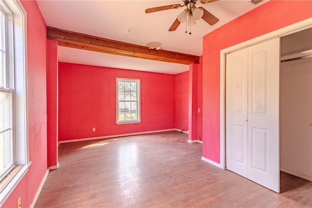 unfurnished bedroom with beamed ceiling, ceiling fan, light hardwood / wood-style floors, and a closet