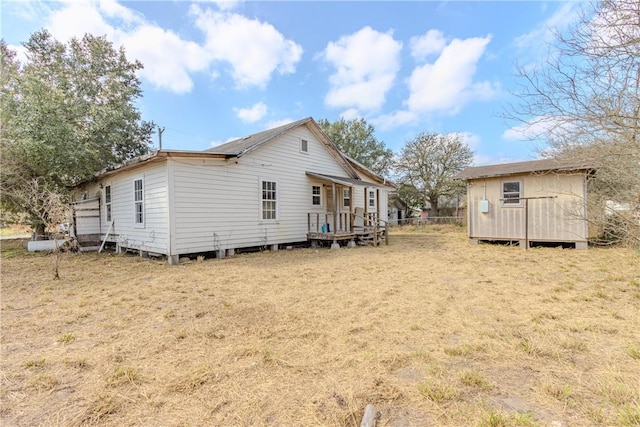 rear view of house with a storage unit and a yard