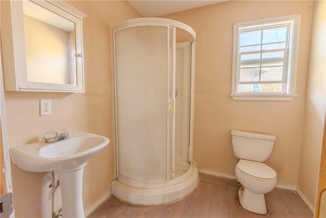 bathroom featuring a shower with door, hardwood / wood-style floors, and toilet