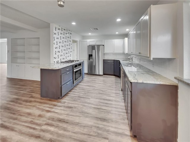 kitchen with appliances with stainless steel finishes, light wood-style floors, visible vents, and a sink