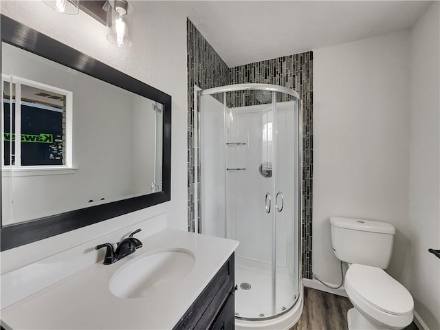 full bath with toilet, a stall shower, wood finished floors, and vanity