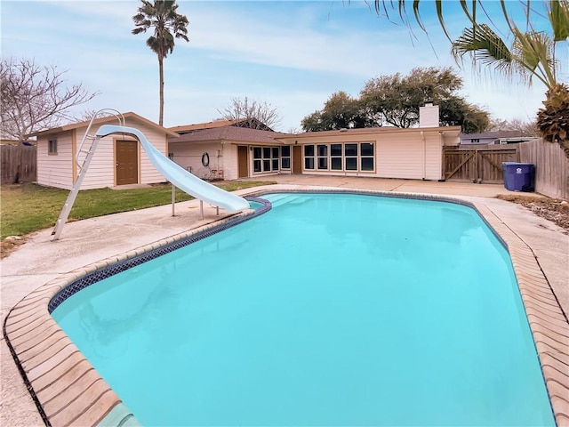 view of swimming pool with a fenced in pool, a water slide, a patio area, and fence