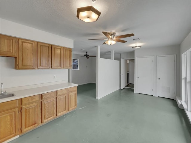 kitchen with light countertops, visible vents, a sink, a textured ceiling, and concrete flooring