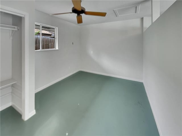 interior space with ceiling fan, baseboards, finished concrete flooring, a closet, and attic access