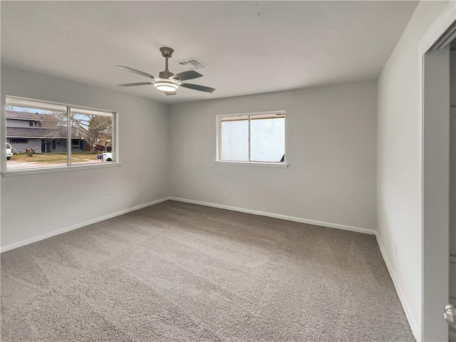 carpeted empty room featuring a ceiling fan, visible vents, and baseboards