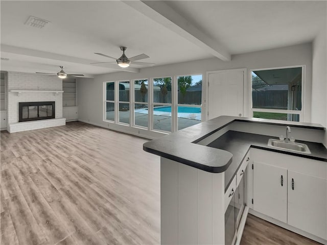 kitchen featuring dark countertops, visible vents, a sink, wood finished floors, and beamed ceiling