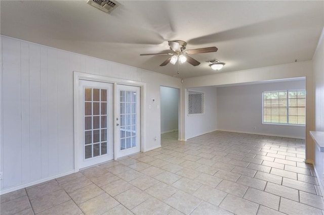 tiled empty room featuring french doors and ceiling fan