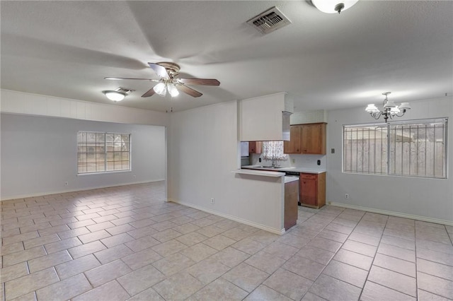 kitchen featuring light tile patterned flooring, ceiling fan with notable chandelier, sink, hanging light fixtures, and kitchen peninsula