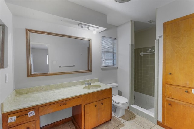 bathroom with tile patterned flooring, vanity, a tile shower, and toilet