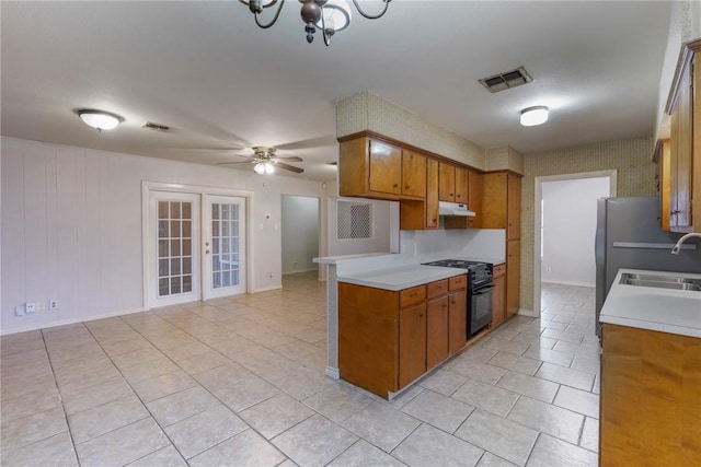 kitchen with sink, electric range, light tile patterned flooring, ceiling fan with notable chandelier, and french doors