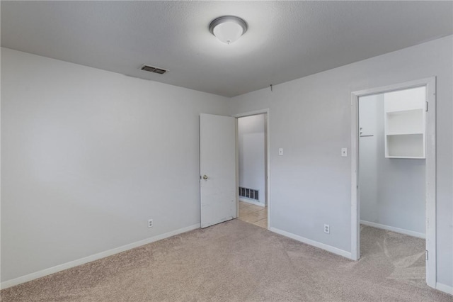 unfurnished bedroom with a spacious closet, light colored carpet, and a closet