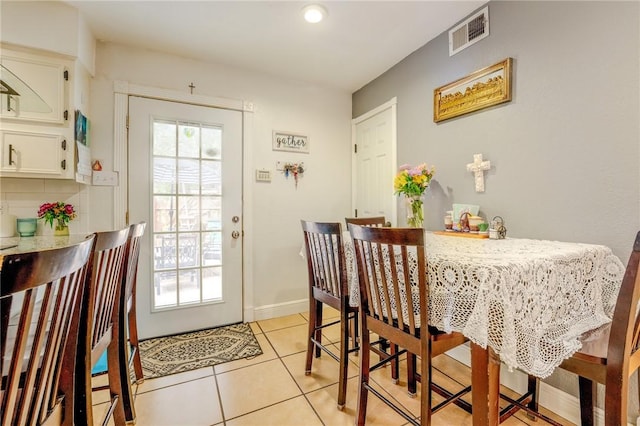 dining space featuring light tile patterned floors, visible vents, and baseboards