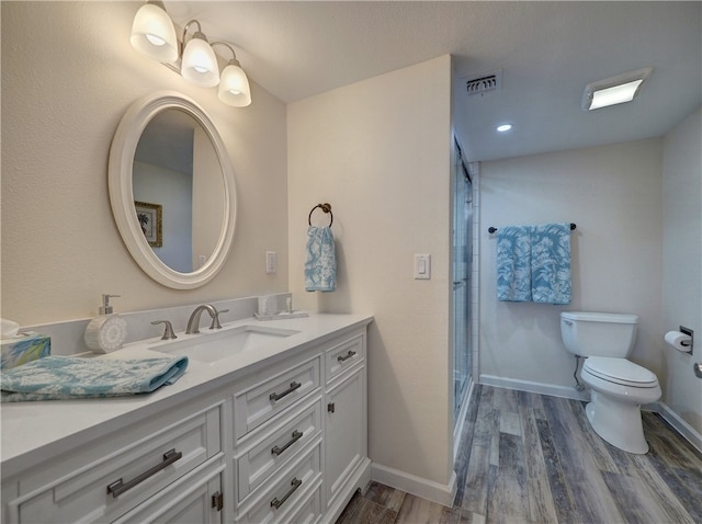 bathroom featuring wood-type flooring, vanity, toilet, and a shower with shower door