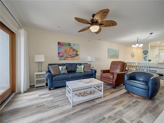 living room featuring ceiling fan with notable chandelier, light hardwood / wood-style flooring, and plenty of natural light