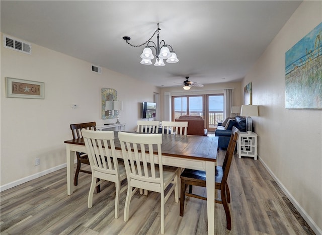 dining area with wood-type flooring and ceiling fan with notable chandelier