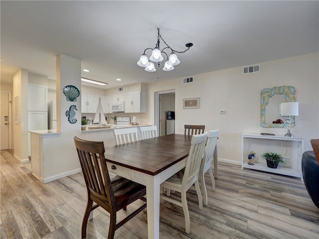 dining room featuring an inviting chandelier and light wood-type flooring