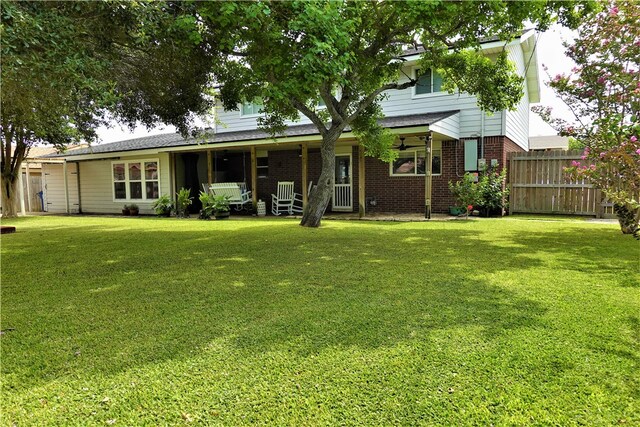 rear view of property featuring covered porch and a yard