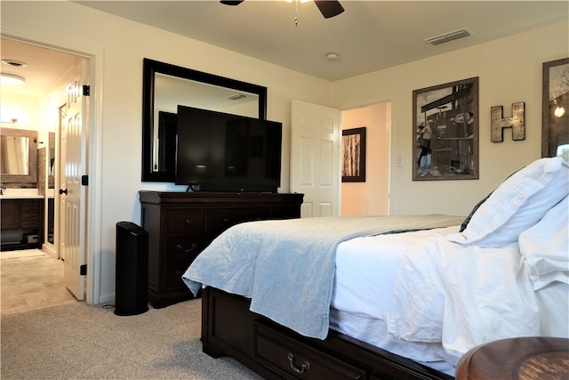 bedroom featuring light carpet, ceiling fan, and ensuite bathroom