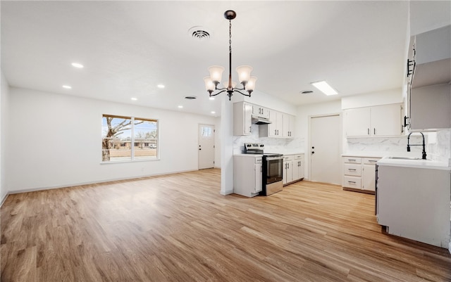 kitchen featuring stainless steel electric range, light hardwood / wood-style flooring, pendant lighting, sink, and white cabinetry