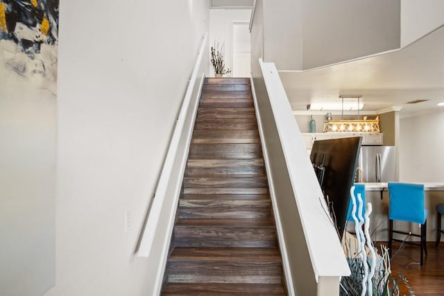 stairs featuring hardwood / wood-style flooring and crown molding